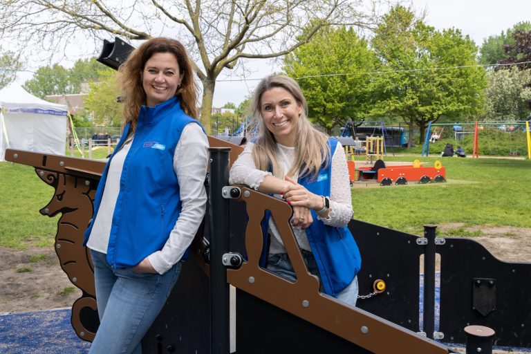 Twee vrouwen in blauwe bodywarmer in een houten speelschhip.