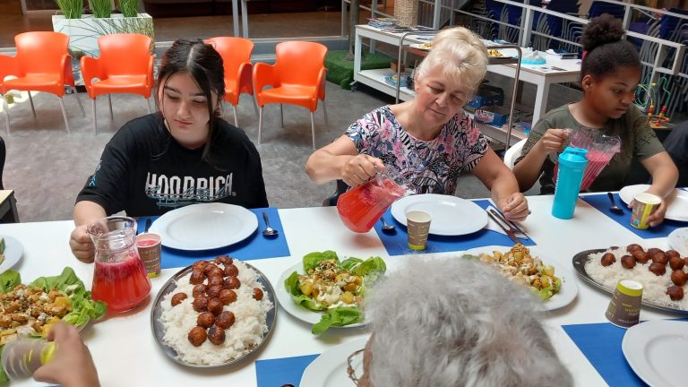 Meisje en oudere mevrouw eten samen aan tafel.