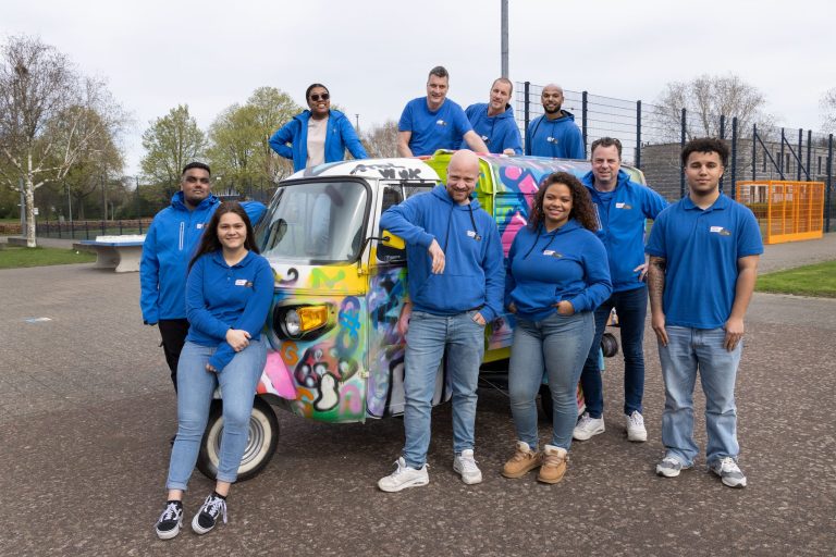 Groep mensen in blauwe jassen voor tuktuk.